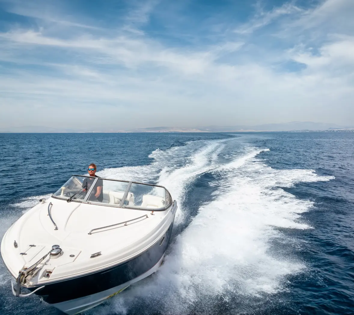 White cruiser carving foamy wake under blue sky