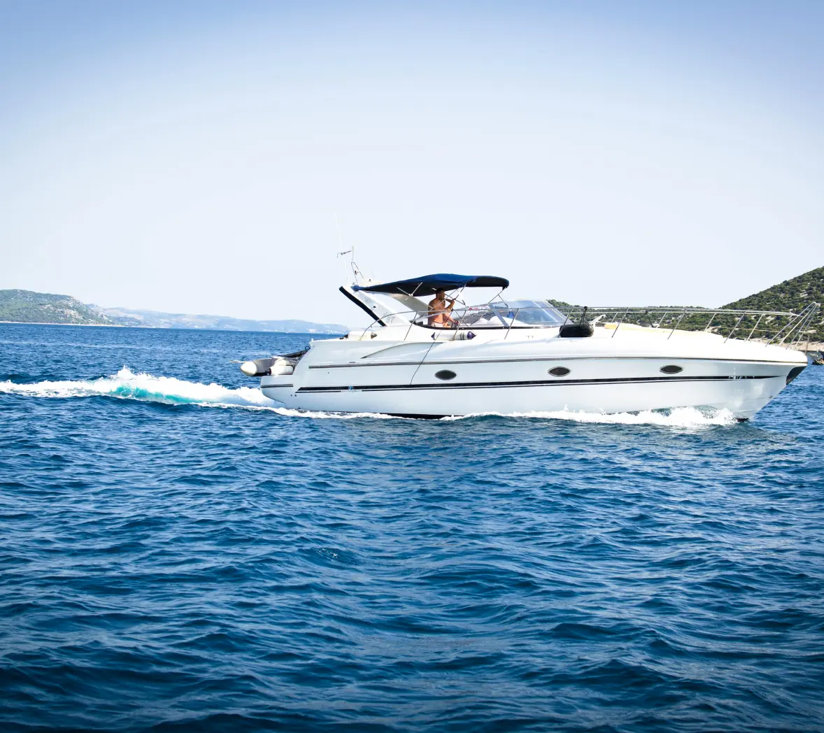 White motor yacht cruising on clear blue sea