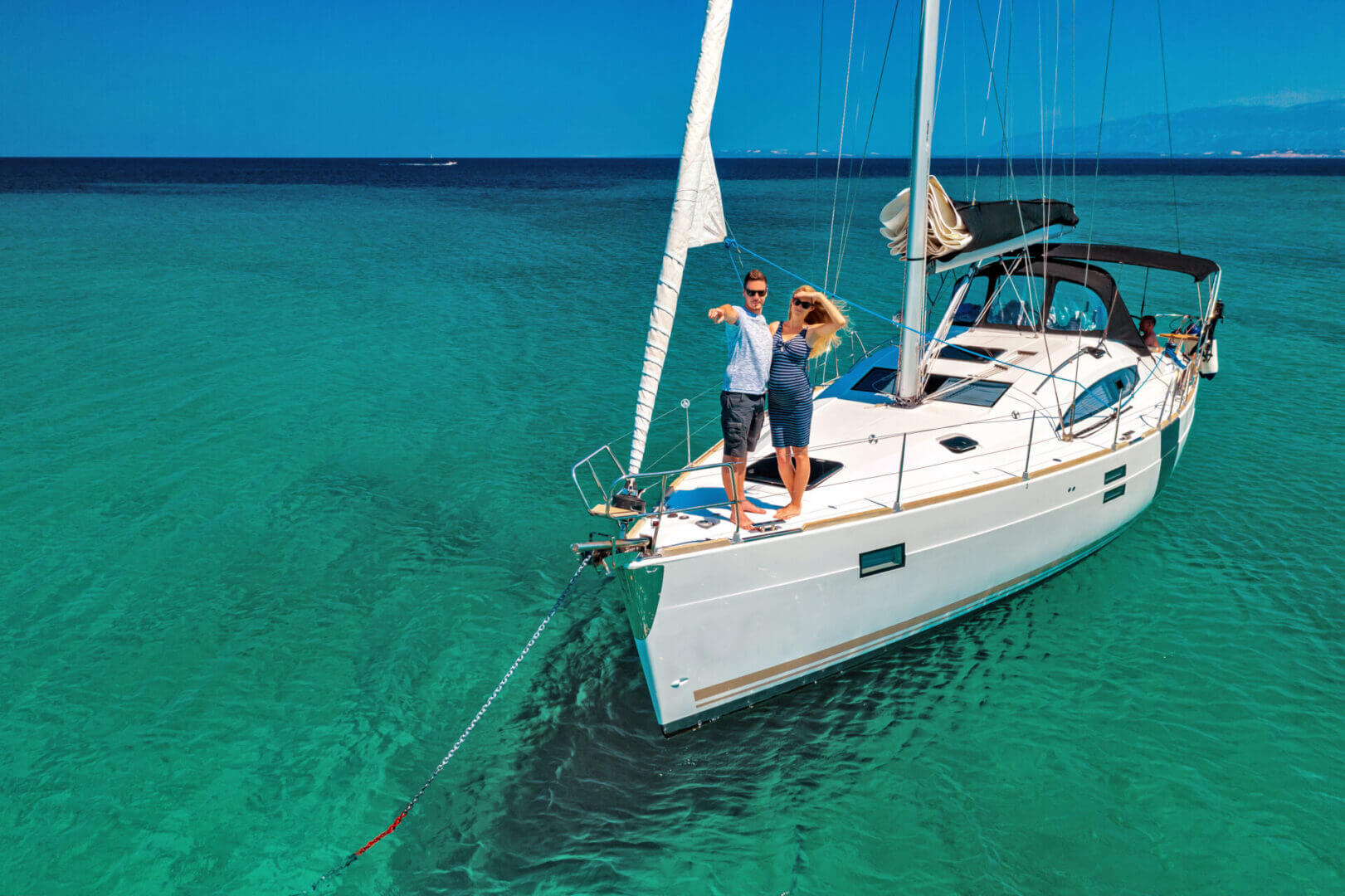 A couple is standing on the bow of their boat.